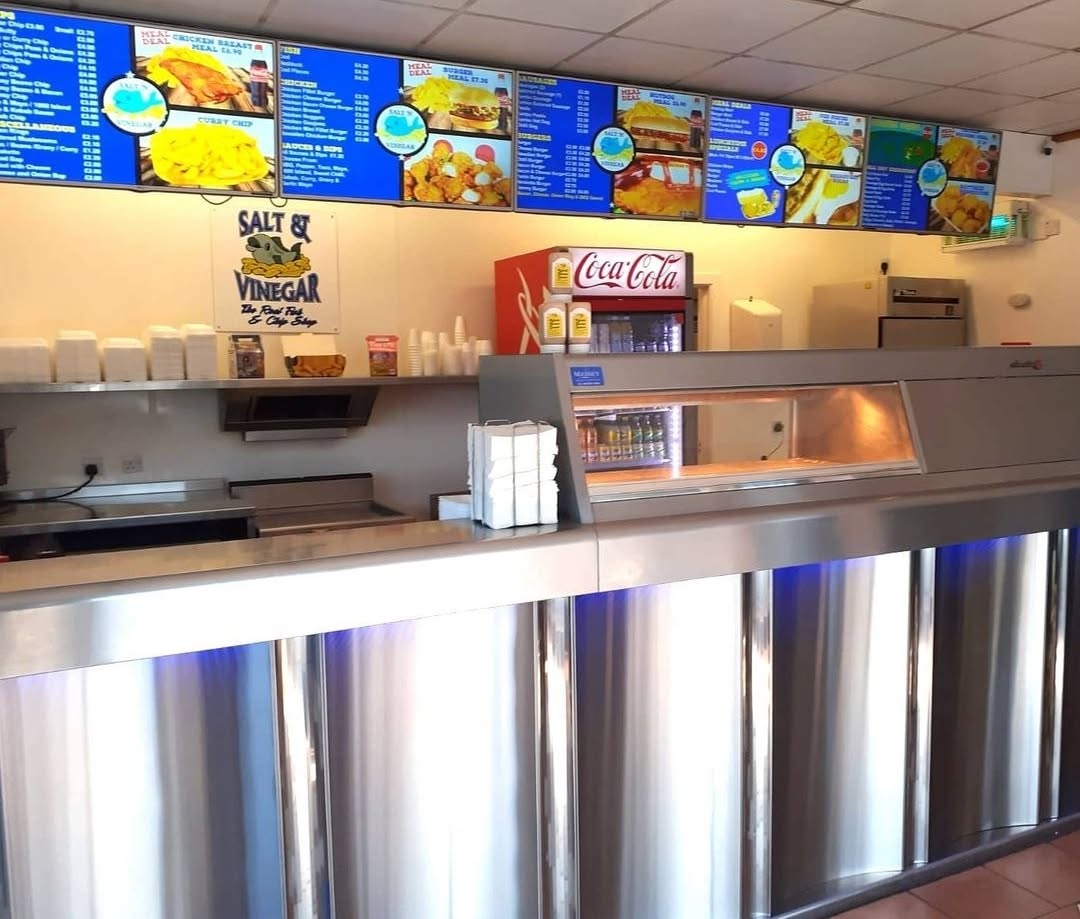 Inside Salt n Vinegar — polished stainless steel counters below the blue menu boards